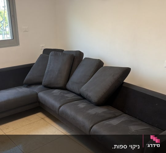 ספה כהה בחדר עם חלון ורצפת קרמיקה